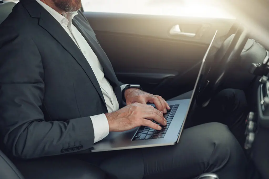 Man on lap top in car trading stock
