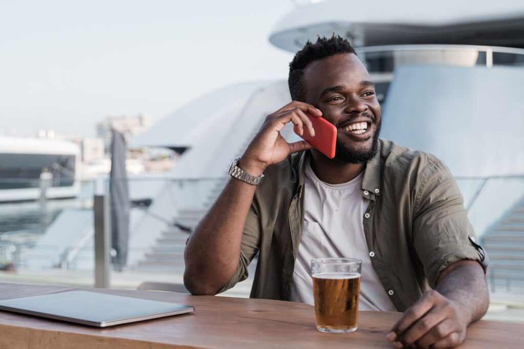 young-man-drinking-beer-at-bar-using-mobile